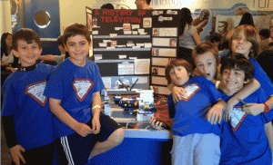 The Super Sonic Seniors posing, sort of, in front of their poster and LEGO model at the Jr. FLL Expo.