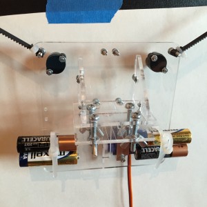 Pen carriage suspended by timing belt. The (dead) batteries are only for weight. Ball casters provide balance, and a 9g servo on the underside lifts the pen off the paper.